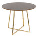 A round walnut wood dining table with a gold metal base.