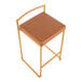 A gold steel counter height stool with a low back and a camel faux leather seat.