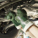 A pair of green nitrile work gloves with white cuffs being worn while performing automotive maintenance.