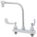 A chrome T&S deck mount faucet with two gooseneck faucets and lever handles.
