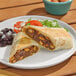 A beef burrito cut in half, served on a plate with black beans, lettuce, and tomato.