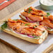 A sandwich made with honey smoked salmon fillet, cream cheese, red onions, capers, and dill on a baguette.