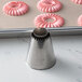 A metal piping tip with a serrated edge, used for decorating pastries and cakes.