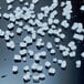 A collection of hard nugget ice pieces scattered on a reflective black surface.