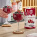 A 1-liter carton of Island Oasis Wildberry Pom Beverage Mix is shown next to a glass of red frozen drink garnished with fresh berries.