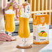 A carton of Island Oasis Mango Beverage Mix next to two glasses of mango smoothie garnished with whipped cream and mango slices.