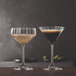 A clear Spiegelau Lifestyle 10.5 oz. coupe glass filled with a sparkling beverage, shown next to a martini glass.