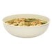A large white round ribbed bowl filled with pasta and vegetables.