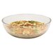 A large clear ribbed round plastic bowl filled with pasta and vegetables.