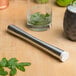 A stainless steel muddler with a white tenderizer head, used for crushing ingredients in cocktails.