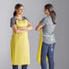 A yellow lightweight vinyl dishwasher apron being modeled from the front and back.