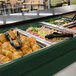 A green Cambro buffet with trays of food on a table.