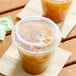 A clear polypropylene reclosable strawless lid on a plastic cup filled with iced beverage.