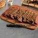 A sliced plant-based vegan steak slab on a wooden cutting board with a serving fork.