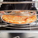 A person holding a pizza on an American Metalcraft wide rim pizza pan.