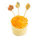 A cupcake decorated with orange frosting and three bamboo cocktail picks featuring fall leaves and a pumpkin design.