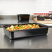 A Vollrath black plastic food pan containing vegetables.