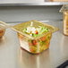 A Vollrath amber plastic food pan with broccoli inside on a counter.