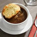 A bowl of French onion soup topped with a slice of toasted bread and melted cheese.