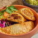 A plate of Brisas beef empanadas with a flour shell, served with a side of fresh vegetables.