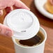 A white plastic Solo Traveler lid being placed on a disposable coffee cup.