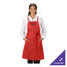 A red customizable poly/cotton cross-back bib apron with three pockets, worn by a person over a white shirt.