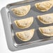 A baking tray with several uncooked buffalo chicken empanadas in flour shells.