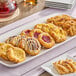 A rectangular white platter with an assortment of mini Danish pastries in various flavors and shapes.