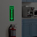 A glow-in-the-dark adhesive vinyl safety label with a down arrow indicating the location of a fire extinguisher.