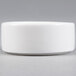 A small, round, white porcelain salt and pepper dish.