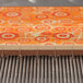 A cutting frame for a confectionery or pastry slicer, shown slicing a layered dessert with an orange patterned top.