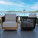 A modern outdoor swivel chair featuring black rope sides, teak wood accents, and light-colored Sunbrella cushions.
