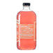 A clear glass bottle filled with pink Stirrings Paloma Mix and sealed with a black cap.