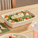 A rectangular compostable fiber take-out container filled with salad.