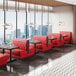 A bright red upholstered double booth with a button tufted back and walnut finishes, designed for restaurant seating.