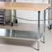 An Advance Tabco wood top work table with a galvanized metal undershelf.