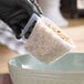 An 8 oz. polypropylene measuring cup filled with a granular substance being poured into a bowl.