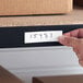 A white magnetic write-on label being applied to a shelf edge.