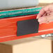 A rectangular magnetic label holder being placed on a steel shelving unit.