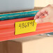A yellow magnetic write-on label being applied to a metal shelf.