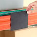 A 4-inch wide magnetic label holder being applied to steel shelving.