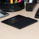 A black pre-inked felt stamp pad in a rectangular plastic case, shown open on an office desk.