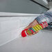 A tube of Flex Seal Flex Caulk being applied along the seam between a kitchen countertop and backsplash.
