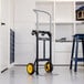 A steel convertible hand truck with two yellow wheels and a black frame, designed for heavy-duty lifting and transport.