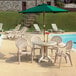 A row of white Grosfillex plastic chairs on a patio with a table.