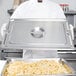 A chef in a white coat holding a silver tray of french fries.