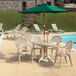 A white Grosfillex Pacific Sandstone fanback resin chair next to a table on a patio.