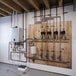 A wall-mounted Rinnai I-SERIES Plus natural gas indoor heat-only boiler system with copper piping and multiple valves installed on a wooden board.