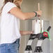 A person using a Lift Ladders aluminum 4-step folding hybrid step ladder while stirring paint in a can.