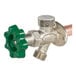 A non-freeze anti-siphon wall hydrant with a green quarter-turn handle and a metallic body.